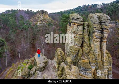 Deutschland, Sachsen-Anhalt, Halberstadt, ein Tourist in einer roten Jacke steht auf der fünf-Finger-Klippe im Klusberg, Bergkette im Vorharz mit Sandsteinhöhlen. Stockfoto