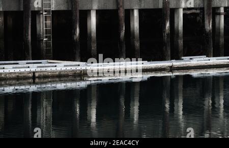 Jachthafen und Fischerdocks mit Leiter, die sich im Wasser spiegelt Stockfoto