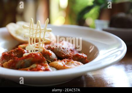 Hausgemachte Spinat Ravioli Pasta mit Wurst in Tomatensauce auf Holz Hintergrund, italienische traditionelle Küche Stockfoto