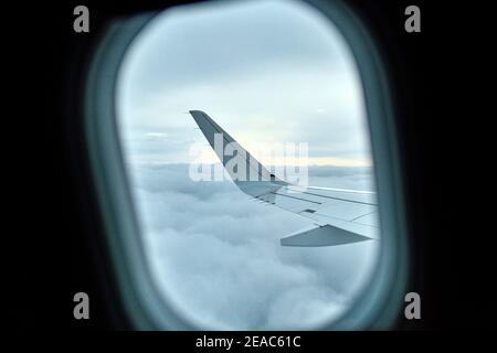 Blick aus dem Fenster eines Flugzeuges auf Wolken und Flugzeugflügel Stockfoto