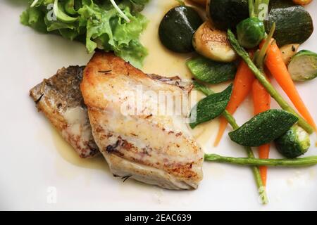 Barschfilet mit gegrilltem Gemüse und Salat auf hölzernen Tisch Stockfoto