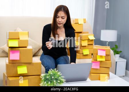 Frau Unternehmerin, die mit Laptop-Computer und mit Kreditkarte im Home Office, (KMU-Unternehmen) Stockfoto