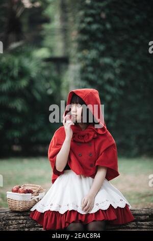 Portrait junge Frau mit Rotkäppchen Kostüm in Green Tree Park Stockfoto