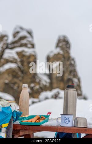 Picknick im Winter liegen Würste auf einem Tisch in einer Tupperware-Box. Daneben befinden sich Thermoskannen. Stockfoto