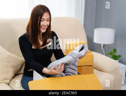 Glückliche Frau öffnen Pappkarton im Wohnzimmer zu Hause, Kauf im Online-Shop Stockfoto