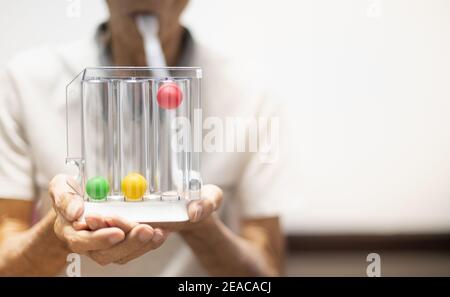 Die alte Patientenhand, die die Tri-Ball Incentive Spirometrie hält, ist ein medizinisches Gerät für die Nachoperation. Die Ausrüstung für Lungenfunktionstests & Pul Stockfoto