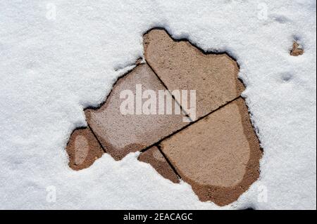 Schnee schmilzt auf Steinplatten Stockfoto