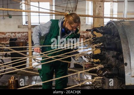 England, Kent, Chatham, die historische Werft, die historische Ropery, weibliche Arbeiter, die Seil an Spinnmaschine anhängen Stockfoto