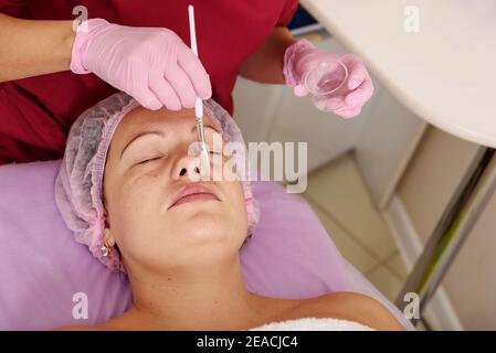 Gesichtspeeling-Maske, Wellness-Schönheitsbehandlung, Hautpflege. Frau bekommt Gesichtsbehandlung von Kosmetikerin im Spa-Salon Stockfoto