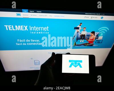 Person hält Smartphone mit Firmenlogo des mexikanischen Telekommunikationsanbieters Telmex auf dem Bildschirm vor der Website. Fokus auf Handy-Display. Stockfoto