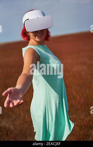 Frau geht in die virtuelle Realität mit Virtual-Reality-Headset. Das Konzept der virtuellen Realität, Simulationen, Verbindung und Kommunikation. Stockfoto