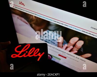 Person, die Smartphone mit dem Logo des US-Pharmaunternehmens Eli Lilly and Company auf dem Bildschirm vor der Website hält. Konzentrieren Sie sich auf die Telefonanzeige. Stockfoto