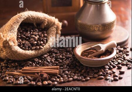 tasse Kaffee und Kaffeebohnen in einem Sack auf Dunkler Hintergrund Stockfoto