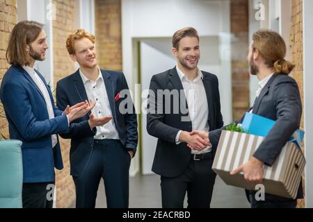 Mann mit Box und drei gratulierenden Kollegen Stockfoto