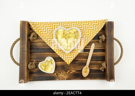 Gelbe Kapseln von Omega 3 liegen auf weißen Keramikplatten In Form der Herzen Stockfoto
