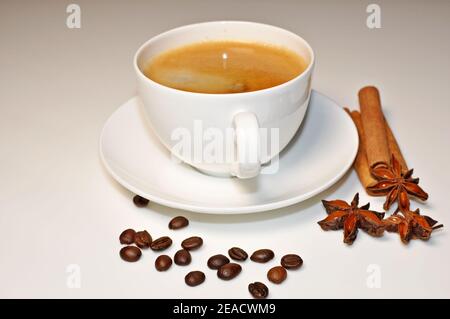 Tasse heißen Kaffee mit Zimt, Kaffeebohnen und Anis Stern Dekoration auf weißem Tischhintergrund. Stockfoto