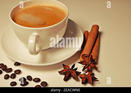 Tasse heißen Kaffee mit Zimt, Kaffeebohnen und Anis Stern Dekoration auf weißem Tischhintergrund. Filter angewendet, Seitenansicht Stockfoto