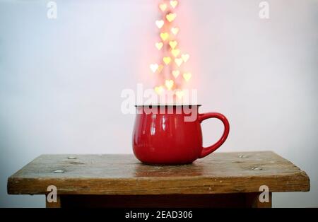 Rote Tasse und herzförmiges Bokeh darüber auf weißem Hintergrund. Valentinstag-Konzept Stockfoto