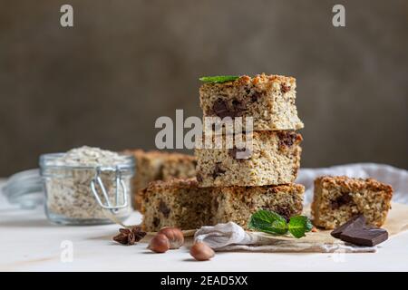 Haferflocken Quadrate mit Schokolade, Nüsse, Stücke von Schokolade und Minze, hellen Beton Hintergrund. Diät-Bars. Gesunde Bäckerei zum Frühstück oder Dessert. Sel Stockfoto