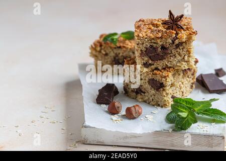 Haferflocken Quadrate mit Schokolade, Nüsse, Stücke von Schokolade und Minze, hellen Beton Hintergrund. Diät-Bars. Gesunde Bäckerei zum Frühstück oder Dessert. Sel Stockfoto