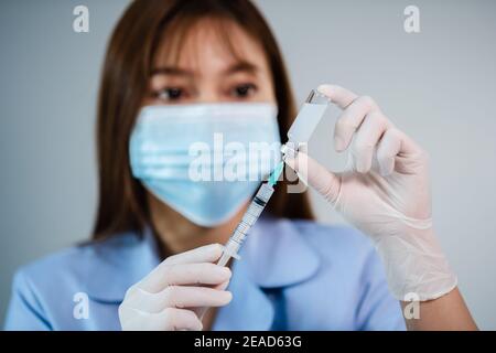 Weibliche Arzt Zeichnung Impfstoffflasche in Spritze Injektion Medizin Stockfoto