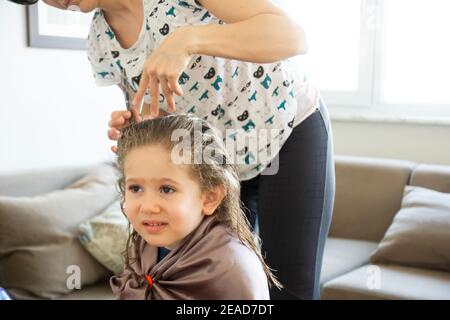 Junge Frau schneidet ihre Tochter die Haare zu Hause während der Pandemie. Bleiben Sie zu Hause. Stockfoto