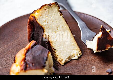 Ein Stück baskischen Käsekuchen auf einem Holzteller verbrannt. Konzept der spanischen Küche. Stockfoto