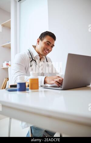 Gut aussehend zuversichtlich männlichen Arzt Arbeit geben Beratung online im Zimmer Im Inneren des medizinischen Zentrums Stockfoto