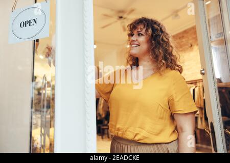 Inhaber eines kleinen Unternehmens, der das Türschild aufdrehte, um es zu öffnen. Die Inhaberin der Modeboutique eröffnet ihr Geschäft für Geschäfte. Stockfoto