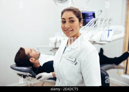 Porträt einer Ärztin mit Patient auf dem Zahnarztstuhl. Selbstbewusste weibliche Zahnärztin in ihrer Klinik. Stockfoto