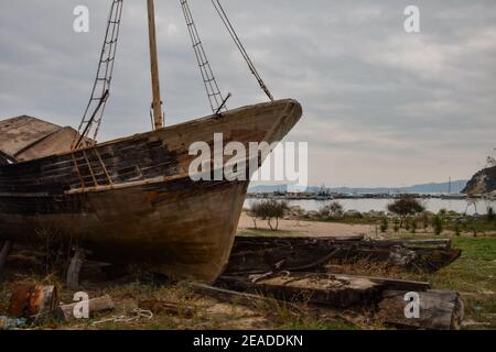 Altes Holzboot verrottet am Ufer in der Nähe des Hafens Stockfoto