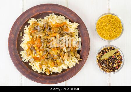 Gekochte Bulgur-Grütze mit geschmortem Gemüse und Pilzen, vegetarisches Essen. Studio Foto Stockfoto