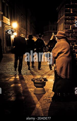 Verschwommene Menschen laufen nachts auf der Straße der antiken Stadt entlang. Monochromes Bild Stockfoto