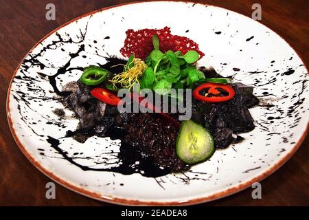 Ceviche-Seabass, mit parfümiertem schwarzem Reis auf Tintenfischtinte Stockfoto