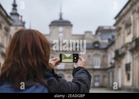 Weibliche Touristen, die ein Foto des Königspalastes von La Granja von San Ildefonso in Segovia, Spanien Stockfoto