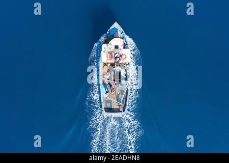Kleines Fischerboot, das über ruhiges glattes Meer segelt, Luftblick. Stockfoto