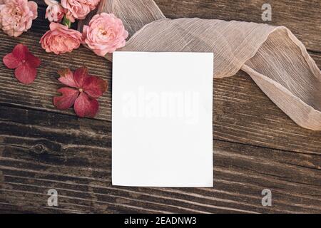 Sommerhochzeit Stillleben Szene. Modell mit leerer Grußkarte. Florale Komposition mit rosa Rosen, Hortensien Blumen auf alten Holztisch Hintergrund Stockfoto