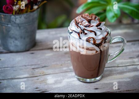 Kakao aus heißer Schokolade im Glas mit Schlagsahne auf Holzhintergrund. Stockfoto