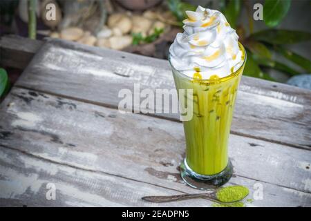 Grüner Tee aus Eis Matcha mit Schlagsahne auf Holztischhintergrund. Stockfoto