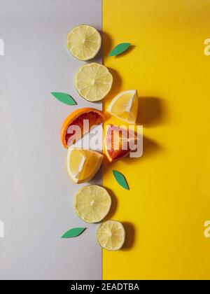 Bunte Frucht Hintergrund Draufsicht. Vertikale Zusammensetzung der Scheiben von roten Orange und Zitrone . Draufsicht auf Zitrusfrüchte auf grauem und gelbem Hintergrund. Illumi Stockfoto