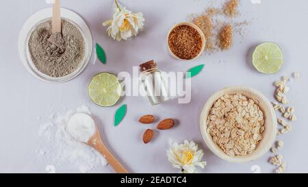 Natürliche Hautpflegeprodukte: Backpulver, Tonpulver, brauner Zucker, Mandelöl, Hafer. Bunte Hintergrund von Naturkosmetik und Blumen. Natürliche in Stockfoto