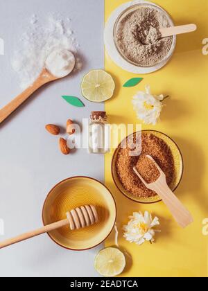 Natürliche Hautpflegeprodukte: Backpulver, Tonpulver, Honig, brauner Zucker, Mandelöl. Bunte Hintergrund von Naturkosmetik und Blumen. Natürliche i Stockfoto