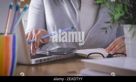 Arbeiten zu Hause, intelligentes Arbeiten. Frau ist niedergelegt und schreibt auf Notebook und tippen Laptop und smartphon auf Schreibtisch. Mädchen verwendet mehr technologische Gerät Stockfoto