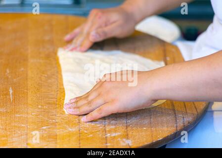 Istanbul, Türkei, Hände einer türkischen Frau, die auf einem Holztisch traditionelles Gebäck von Dought macht Stockfoto