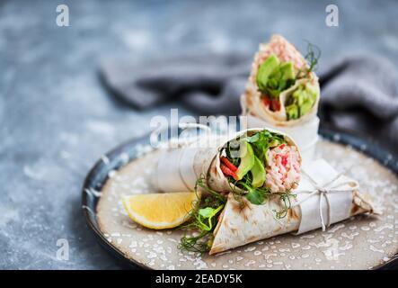 Frische und gesund verpackte Tortilla mit Krabbensalat, Gurke, Avocado, Pfeffer und grünen Kräutern Stockfoto