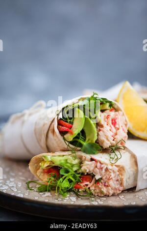 Frische und gesund verpackte Tortilla mit Krabbensalat, Gurke, Avocado, Pfeffer und grünen Kräutern Stockfoto