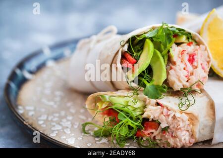 Frische und gesund verpackte Tortilla mit Krabbensalat, Gurke, Avocado, Pfeffer und grünen Kräutern Stockfoto