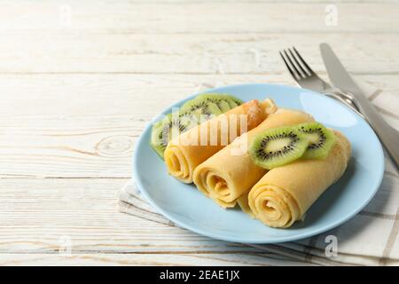 Konzept des Frühstücks mit Teller Crepes Brötchen mit Kiwi Scheiben auf Holztisch Stockfoto