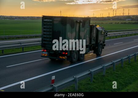 Militär-LKW fährt auf der Autobahn bei Sonnenuntergang Stockfoto