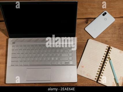 Laptop auf Holztisch mit Mobile und Notebook Stockfoto